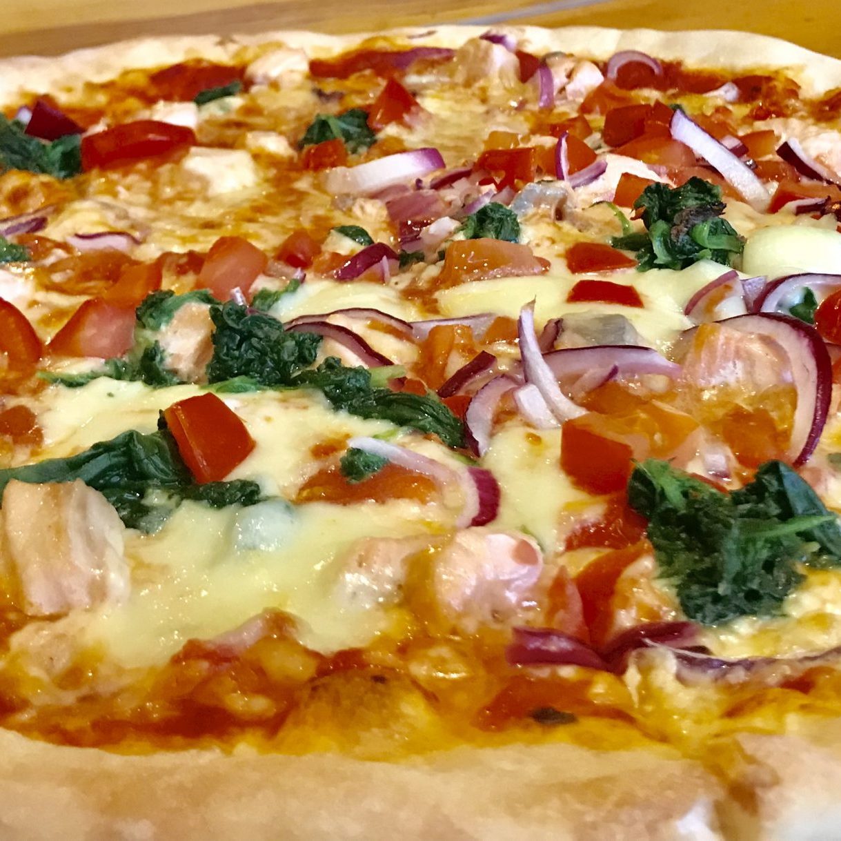 Pizza Norwegia Nr. 94 mit frischem Lachs, Spinat, Tomaten, Mozzarella, Käse